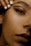 A close-up of a woman's face focusing on the eye area, showcasing detailed makeup with bold eyeliner and well-groomed eyebrows. Her lips are visible in the bottom right, with a natural-looking lipstick. A hand with neatly manicured white nails is positioned near her forehead.