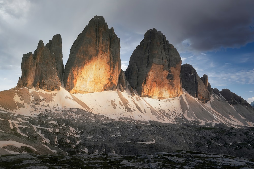 a snowy mountain with a few tall rocks on top