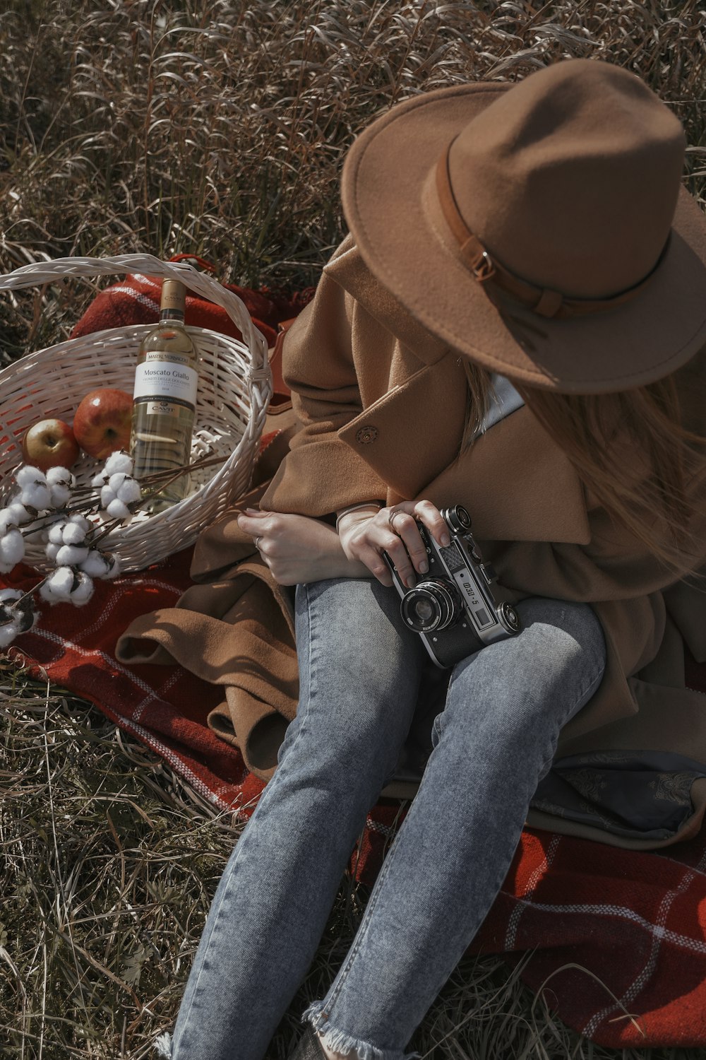 a person sitting on the ground with a camera and a basket of fruit