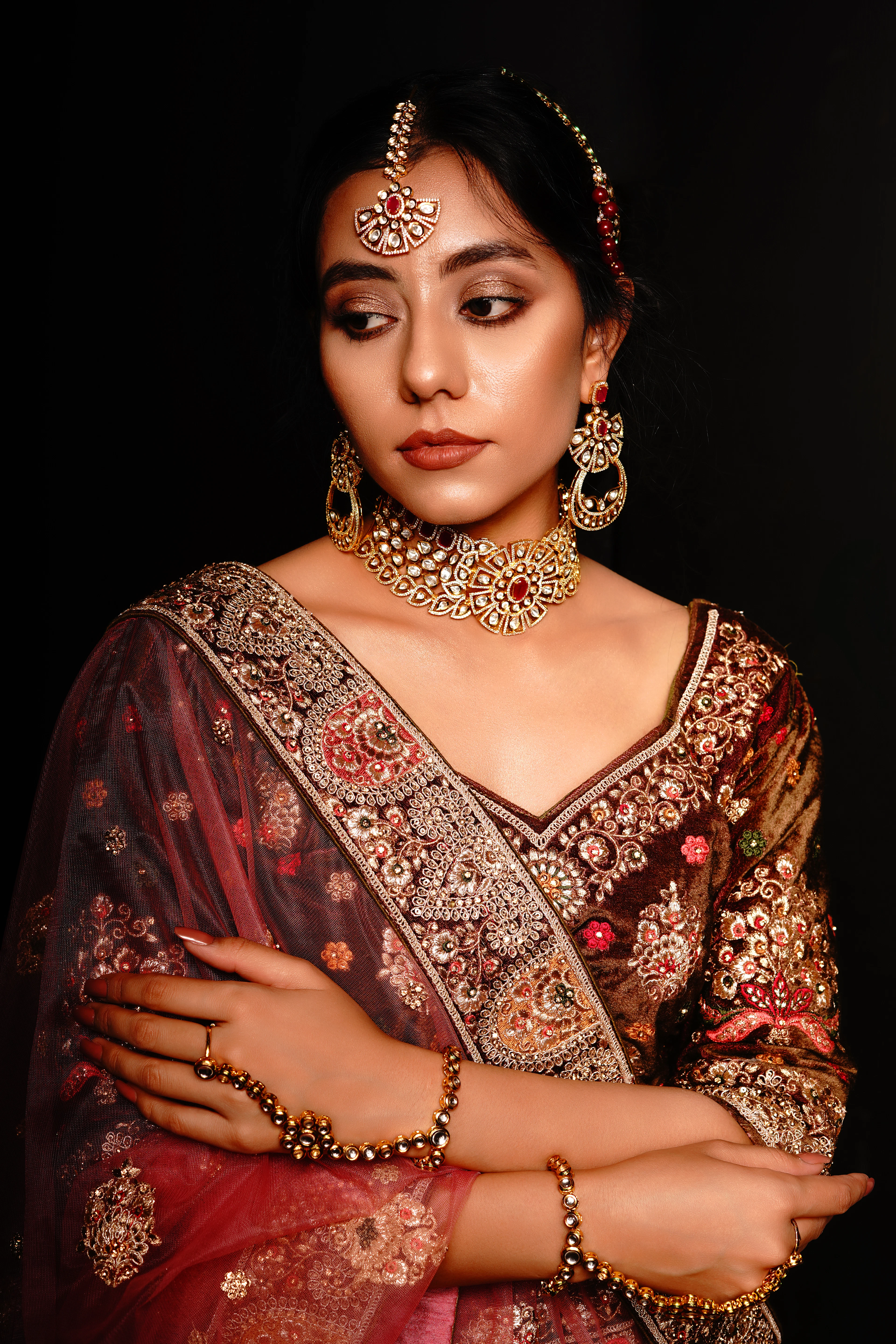 Bride in maroon with arms folded, dark studio