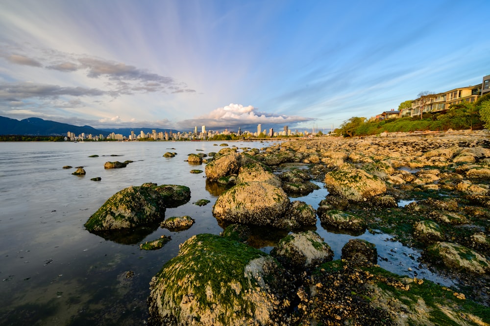 a rocky beach with a city in the background