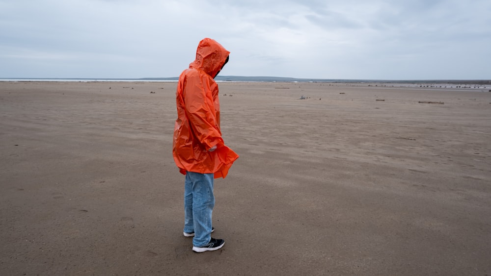 a person wearing a jacket and standing on a sandy beach