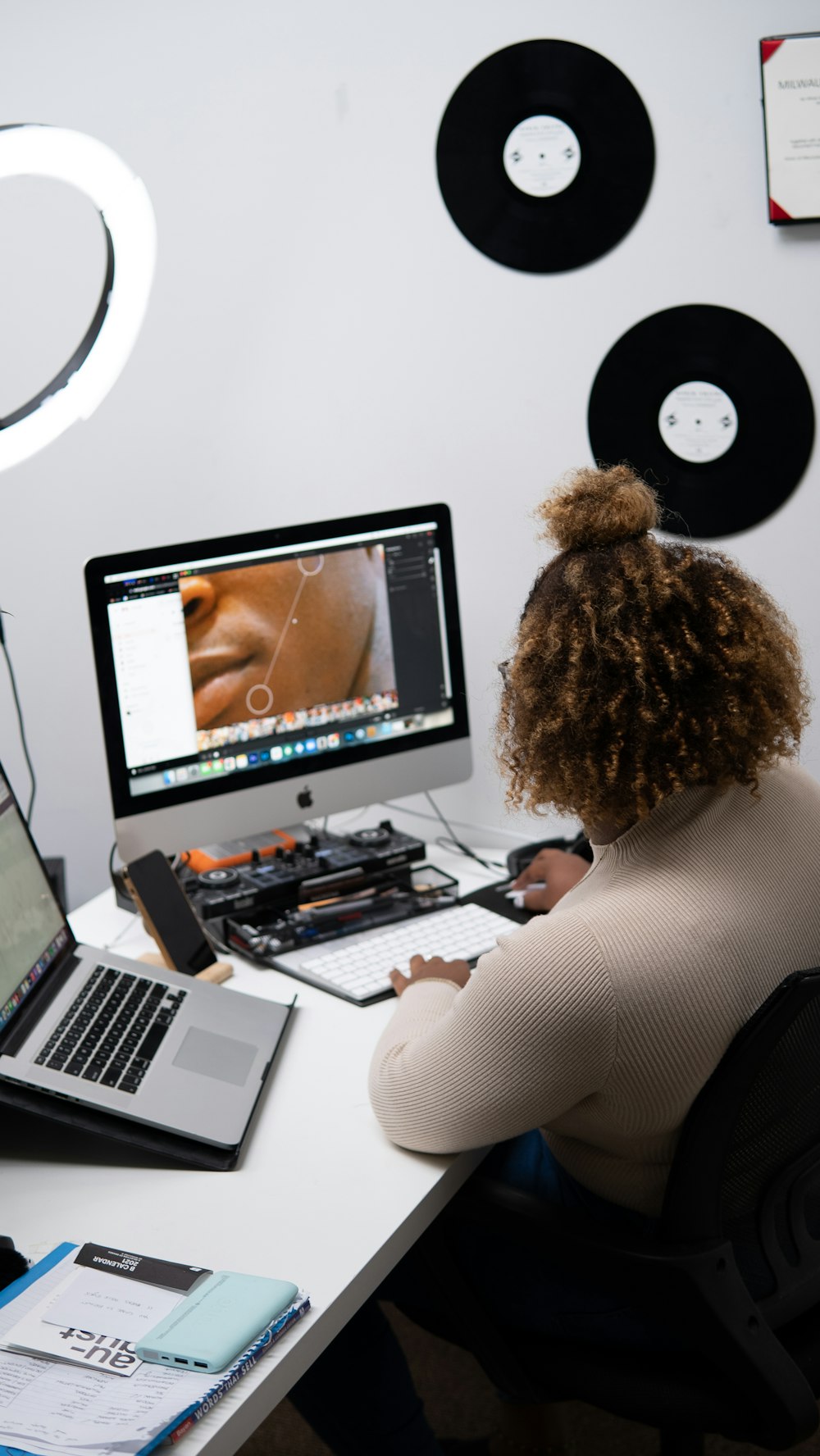 a person sitting at a desk with a computer and a stuffed animal