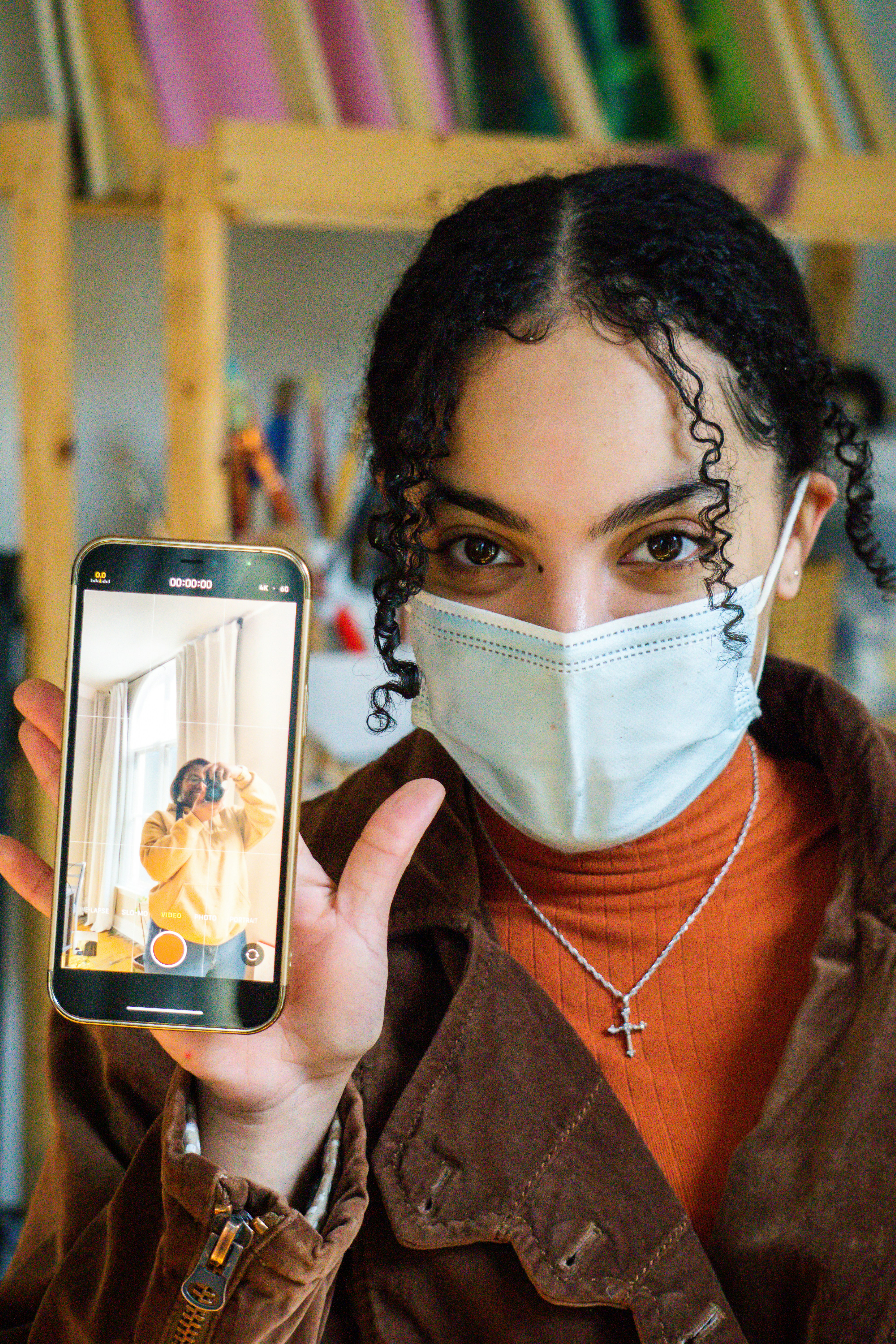 eine Person, die eine Maske trägt und ein Mobiltelefon hält