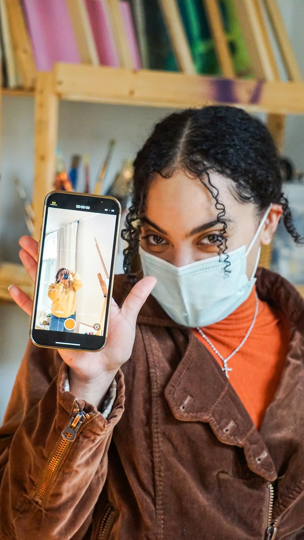 a person with a face mask holding a phone up to the face