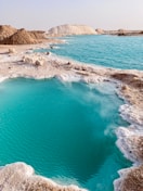 a body of water with rocks and a beach in the background