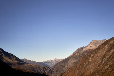 A panoramic view of a mountain range under a clear blue sky with hikers on a trail