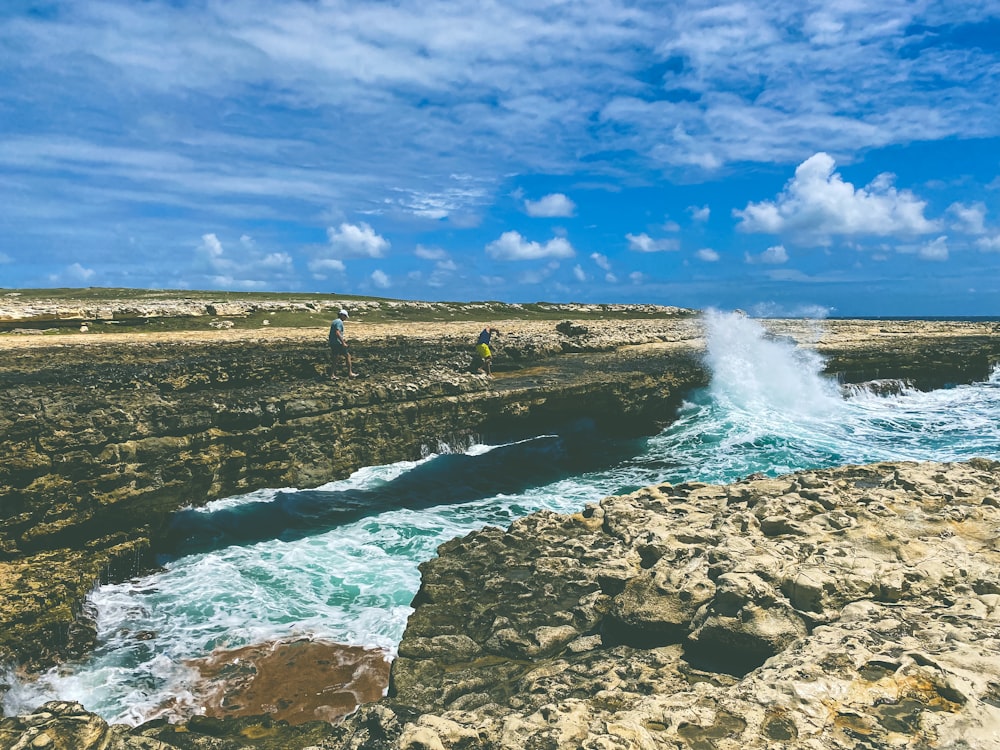 people standing on rocks near a body of water