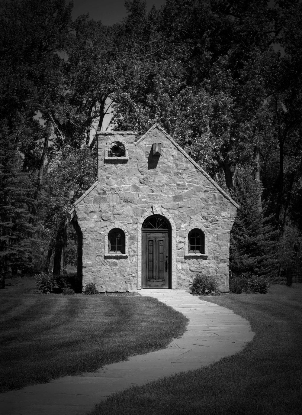 a stone building with a door and windows surrounded by trees
