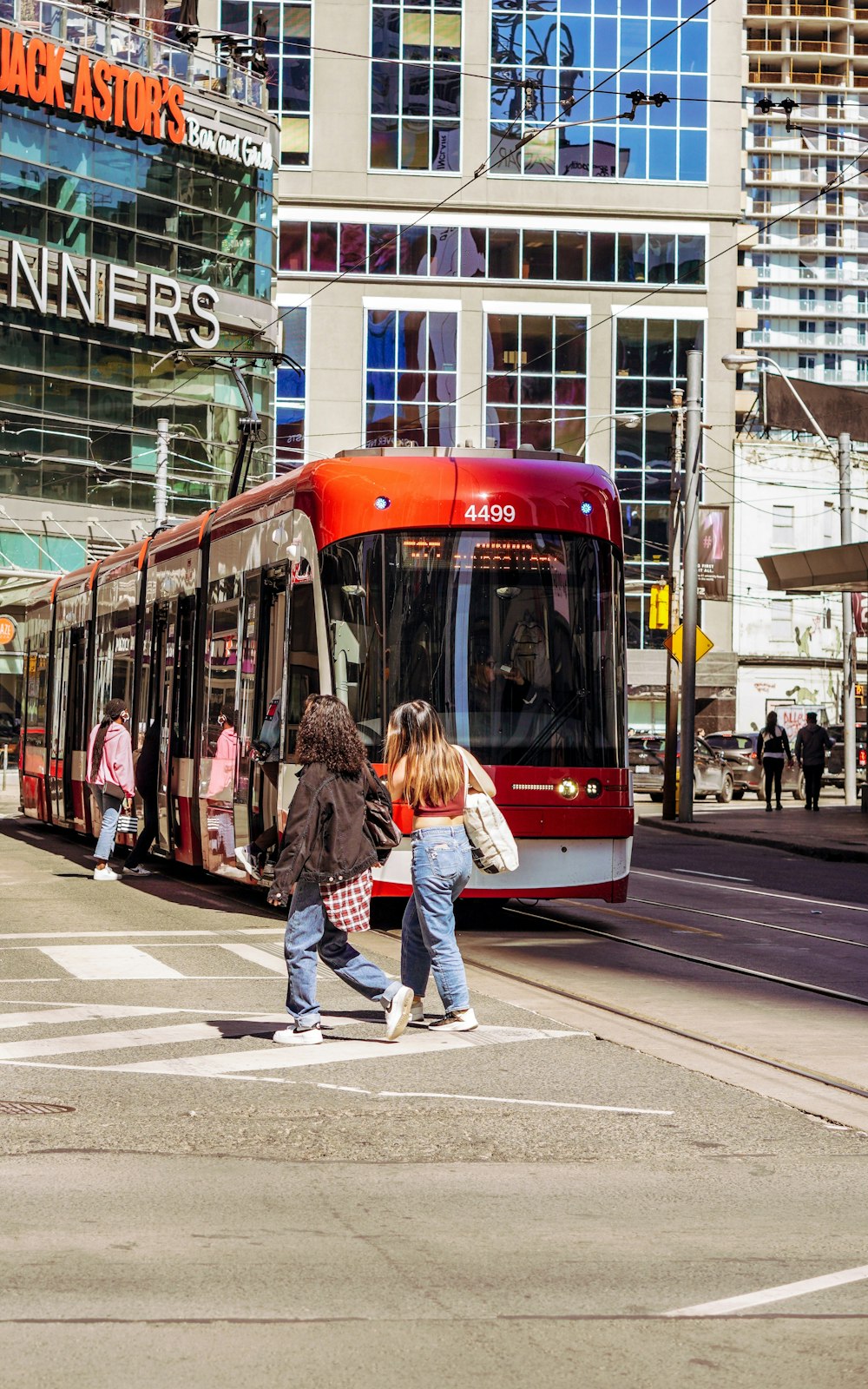 a couple of people walk down a sidewalk next to a bus