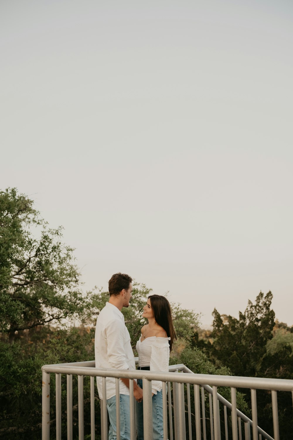 a man and woman kissing on a bridge