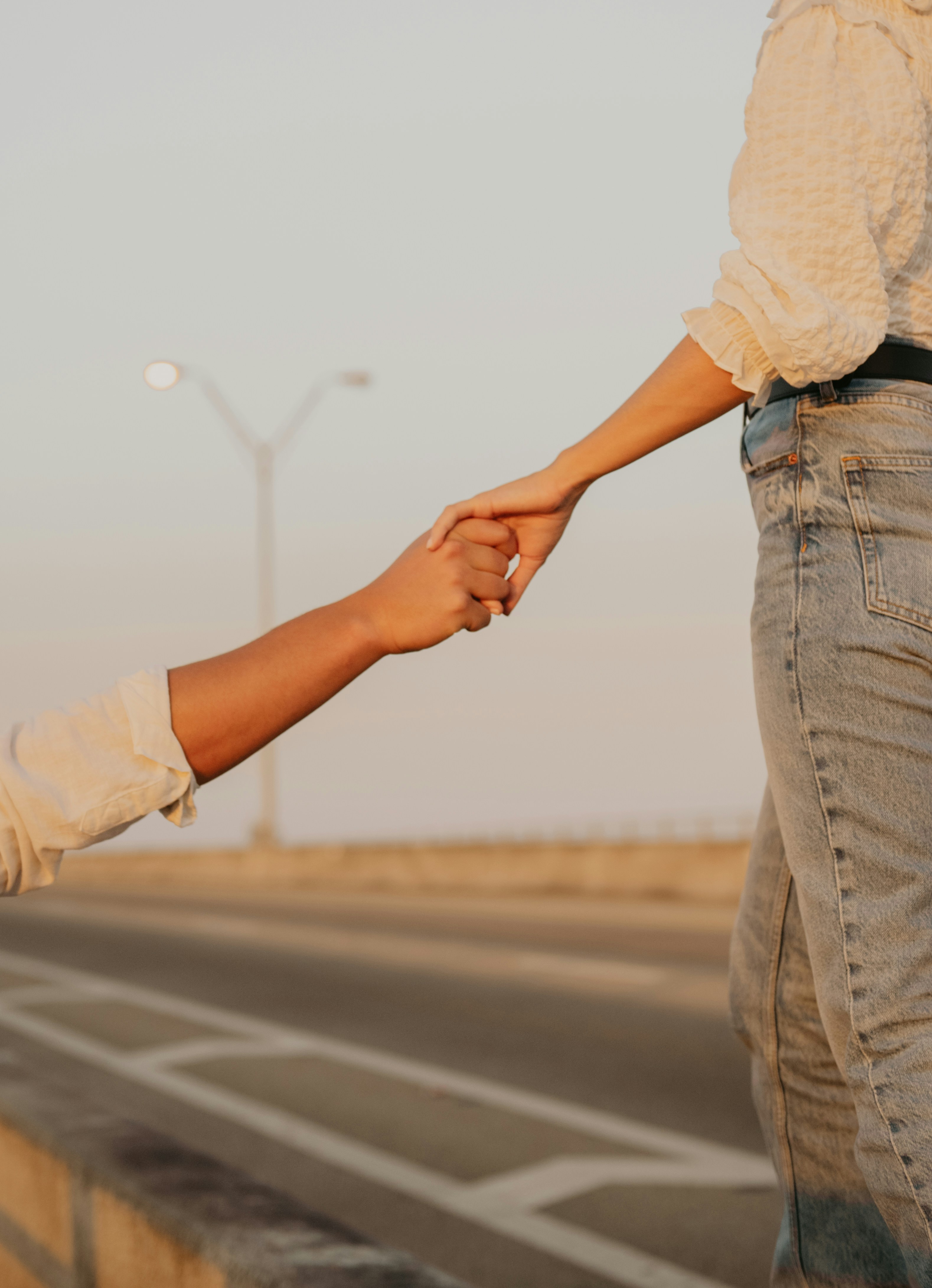 A couple's hands clasped gently, with an abstract, shifting light background representing the influence of the menstrual cycle on relationship dynamics and emotional regulation.