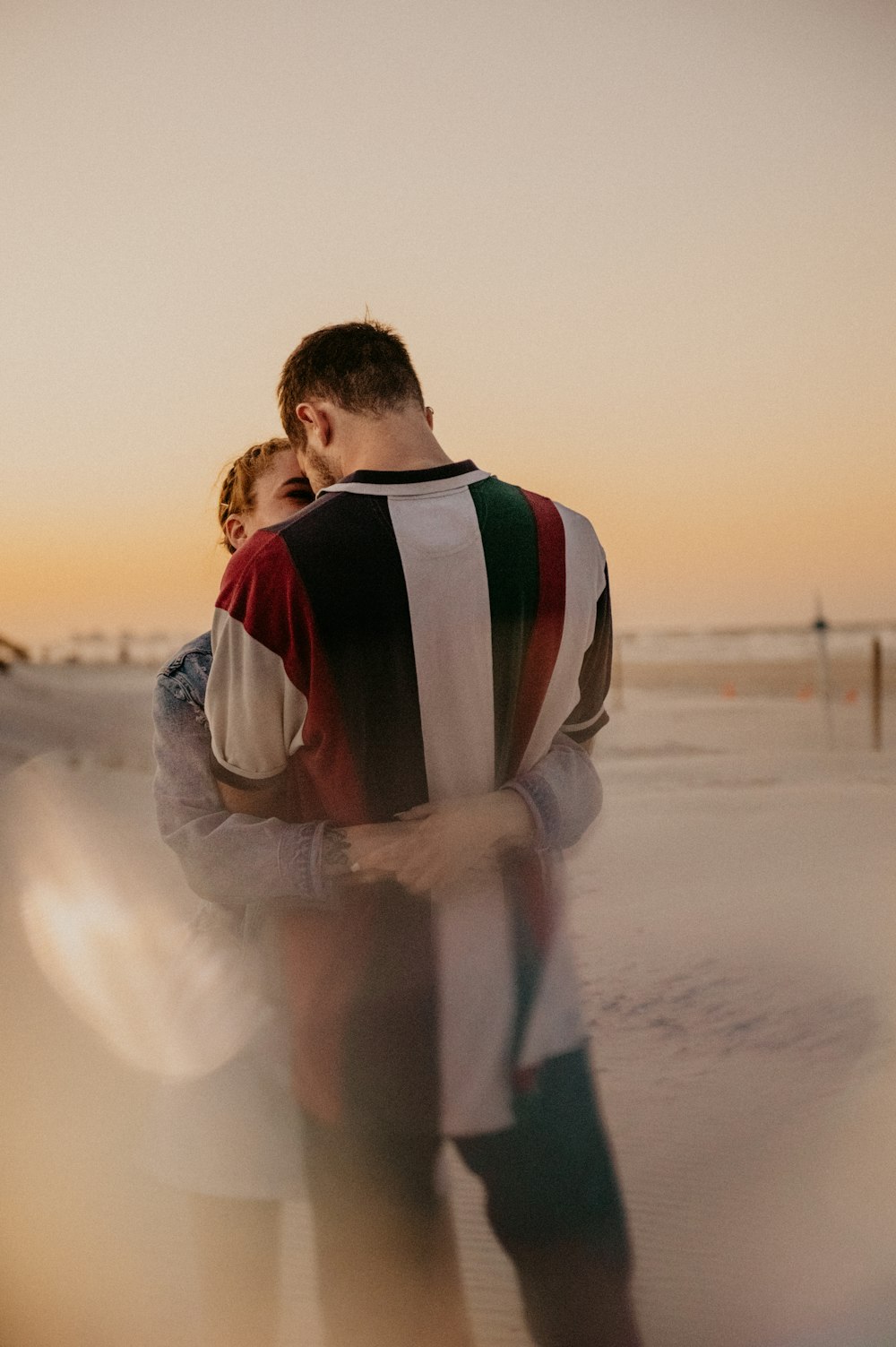 a man and woman kissing on a beach