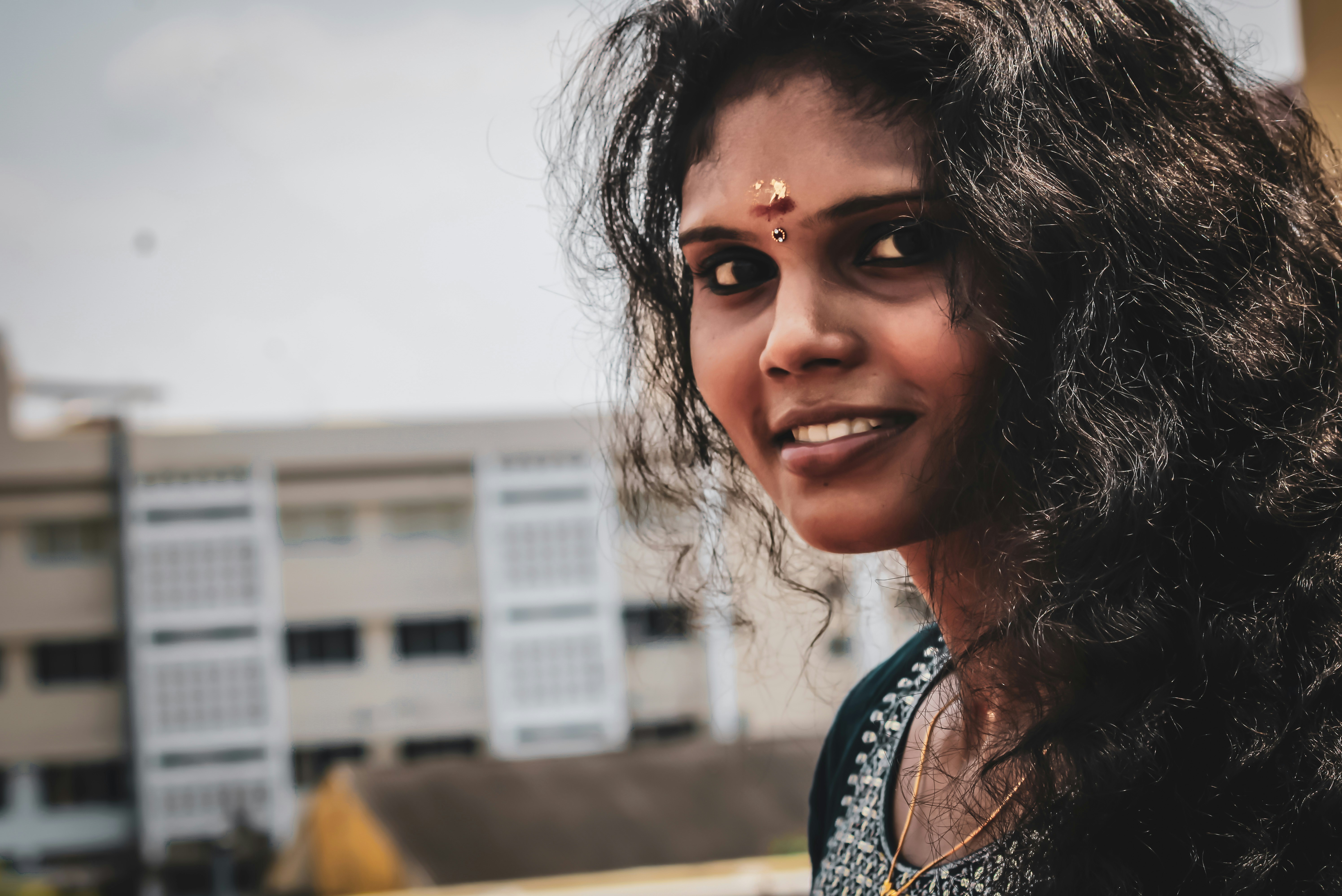 Young Indian woman smiling warmly, casual clothes, outdoor setting