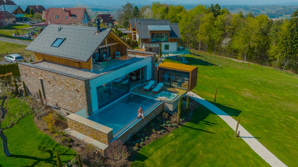 a house with a pool and a lawn with trees and a fence