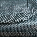 A close-up view of a woven fabric showcasing a detailed pattern and texture with tightly interlaced fibers. The image focuses on the intersection of different textile strands, highlighting the intricate craftsmanship.