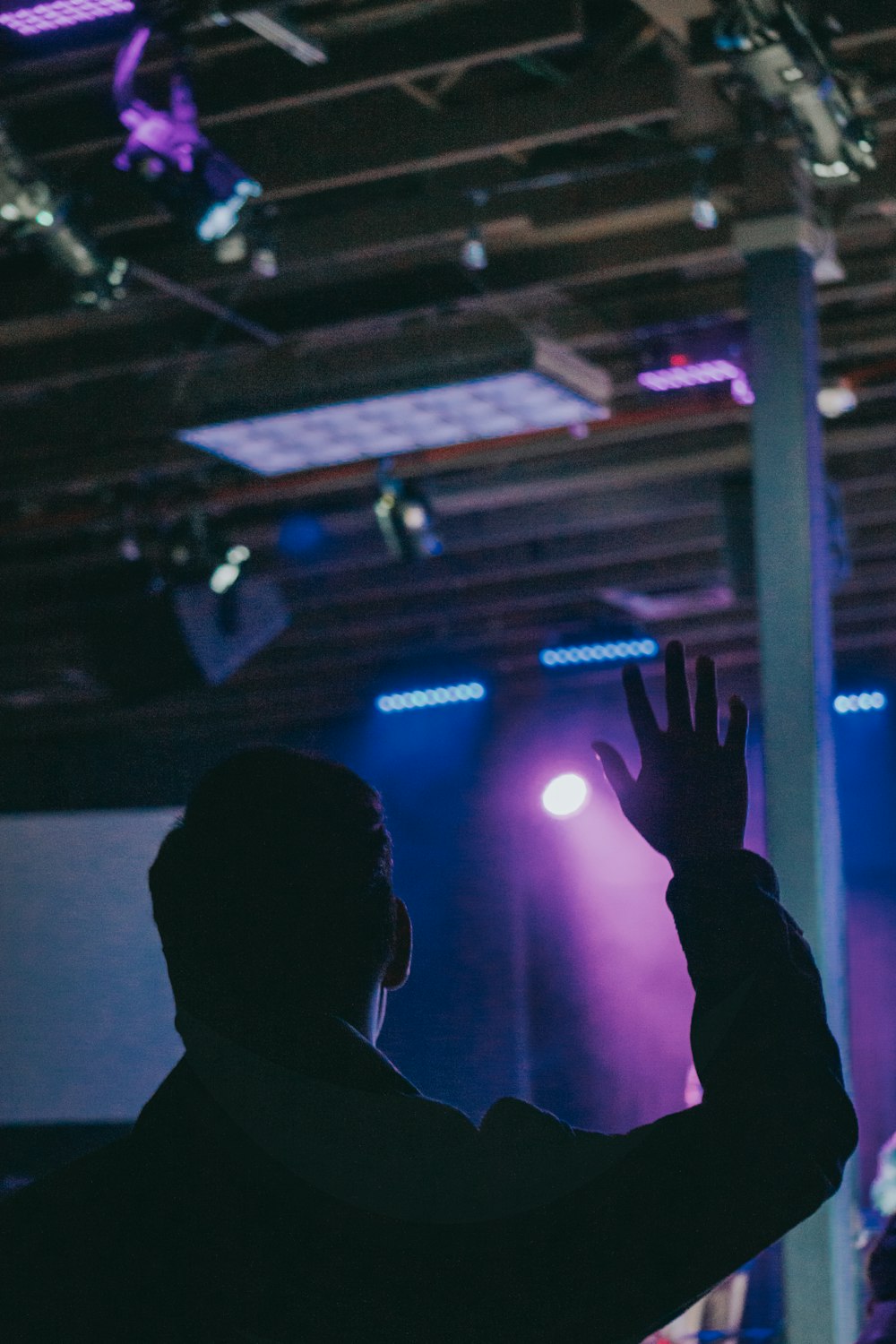 a man with his hands up in front of a stage with lights