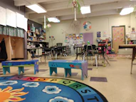 A bright, colorful classroom filled with engaged students and a teacher guiding them.