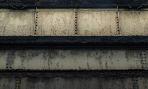 Close-up of handheld laser cleaning device gently removing rust from steel beam on a construction site.
