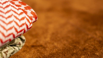 Folded fabric with intricate historical patterns laid out on a textured surface.
