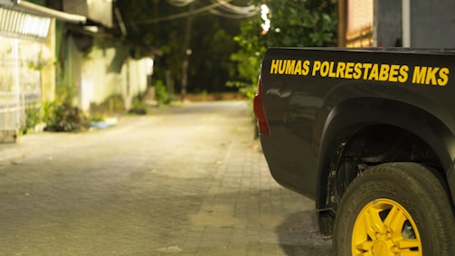 A sturdy tow truck with a sleek trailer parked on a quiet street at dusk.