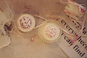 Elegant candle arrangement with warm amber light surrounded by dried flowers and soft cream fabrics.