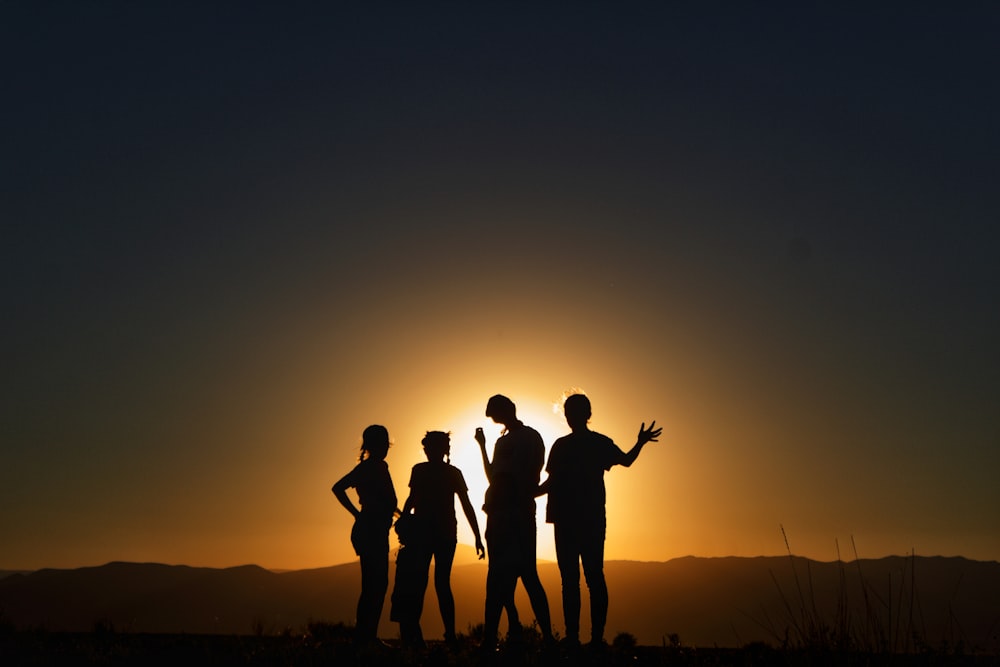 um grupo de pessoas em pé em frente a um pôr do sol
