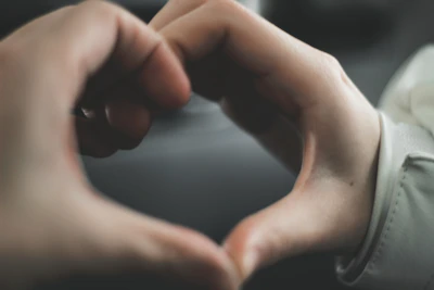 Close-up of two hands forming a heart shape, symbolizing care and connection.