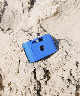 Close-up of a sleek gold detector resting on golden desert sand under a bright sun