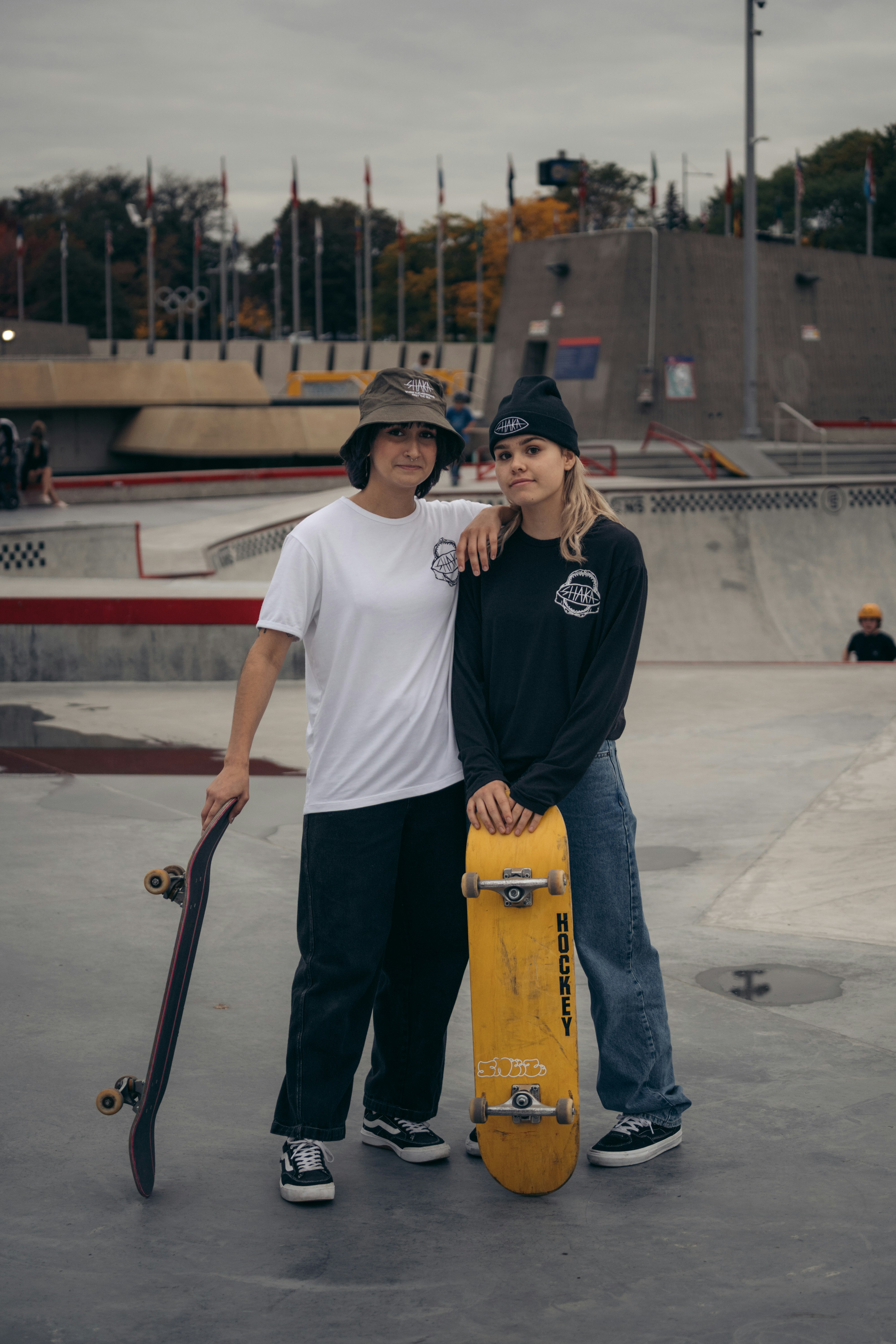 a couple of people stand near each other holding skateboards