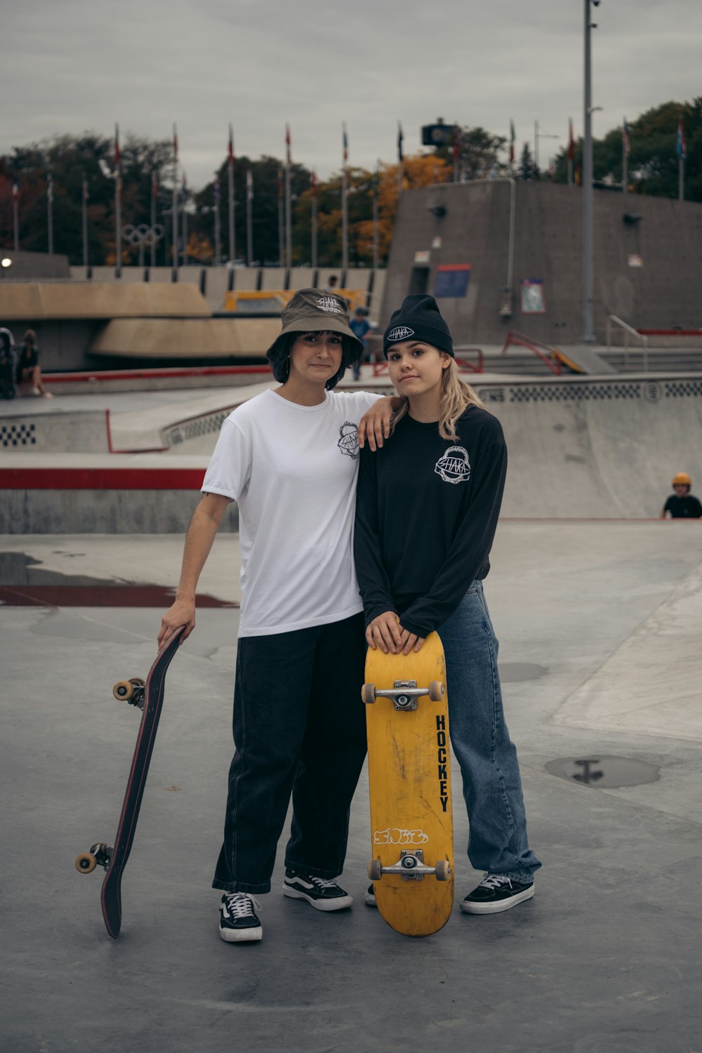 a couple of people stand near each other holding skateboards