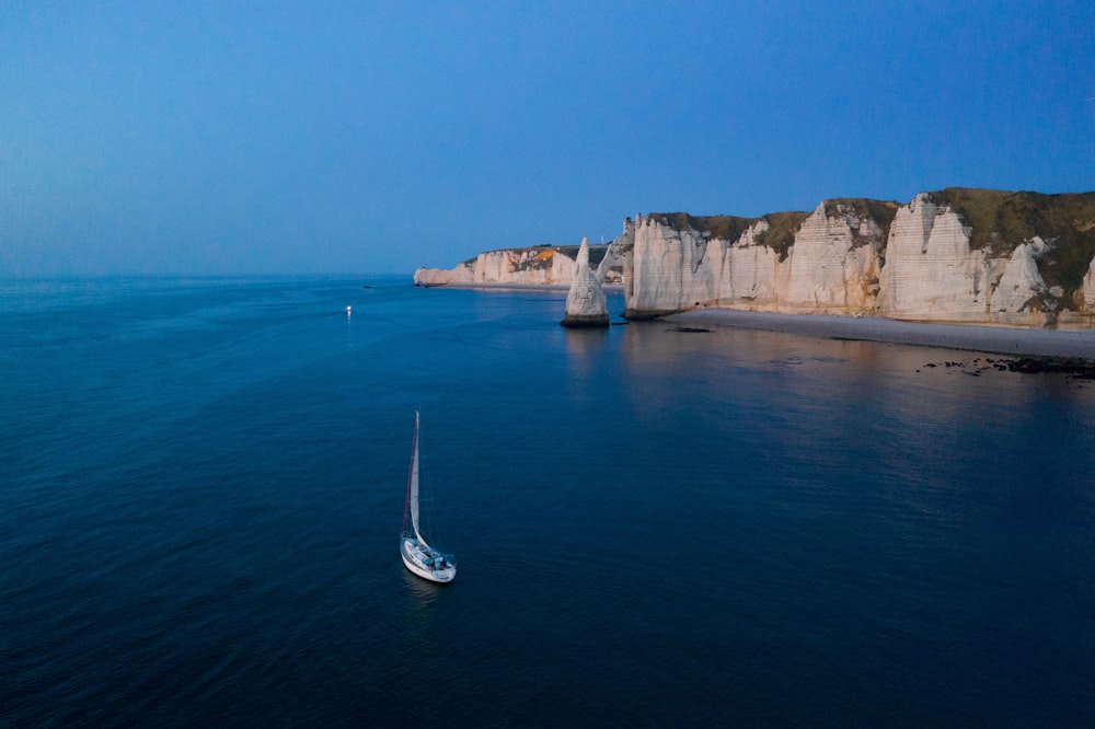 a boat in the water by a rocky cliff