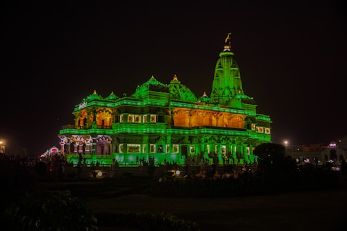 A traditional temple illuminated by warm evening lights with visitors.