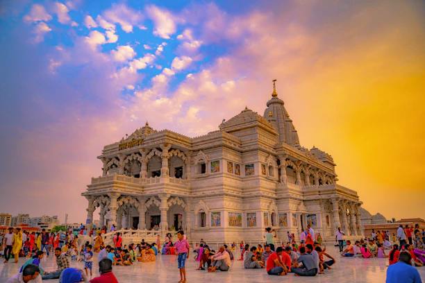 Vibrant image of an Indian temple with travelers admiring the intricate carvings under a warm sunset.