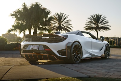 A stunning sports car cruising down a palm-lined street in Miami under clear blue skies.