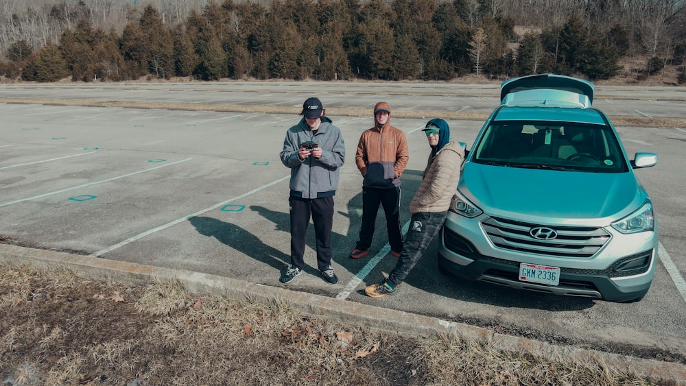 a group of people standing next to a car on a road