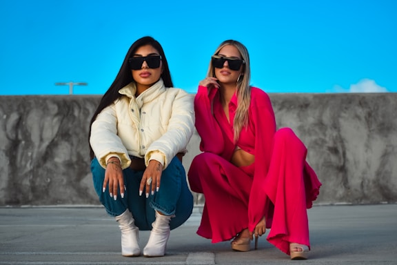two women sitting on a stone wall
