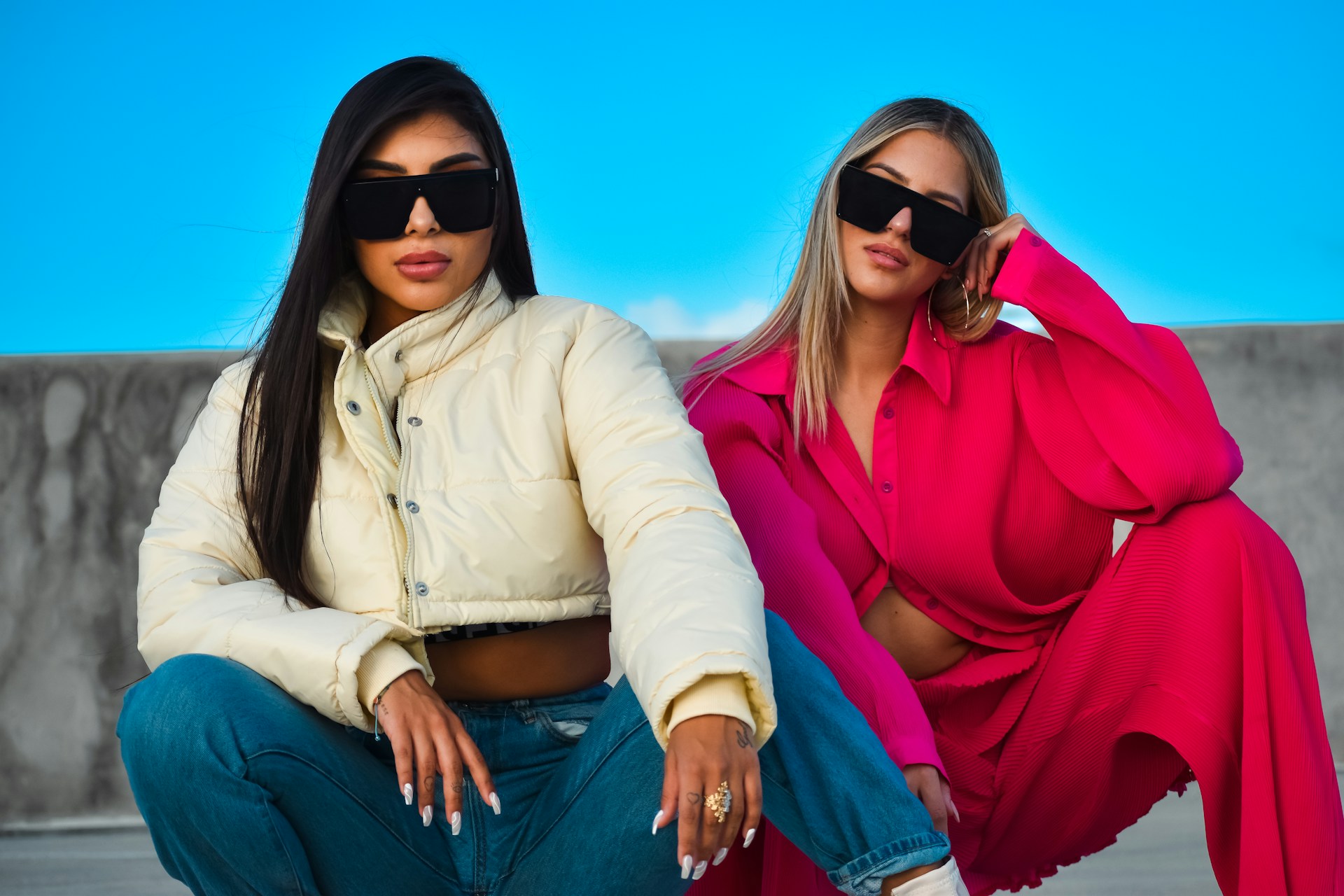two women sitting on a wall