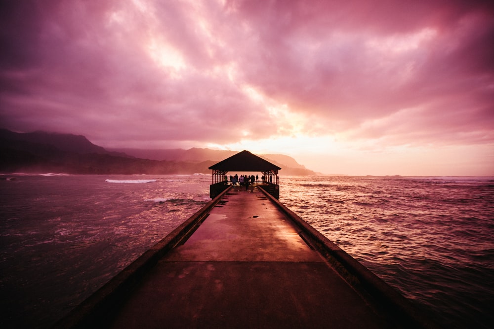 a dock leading to a hut on a beach