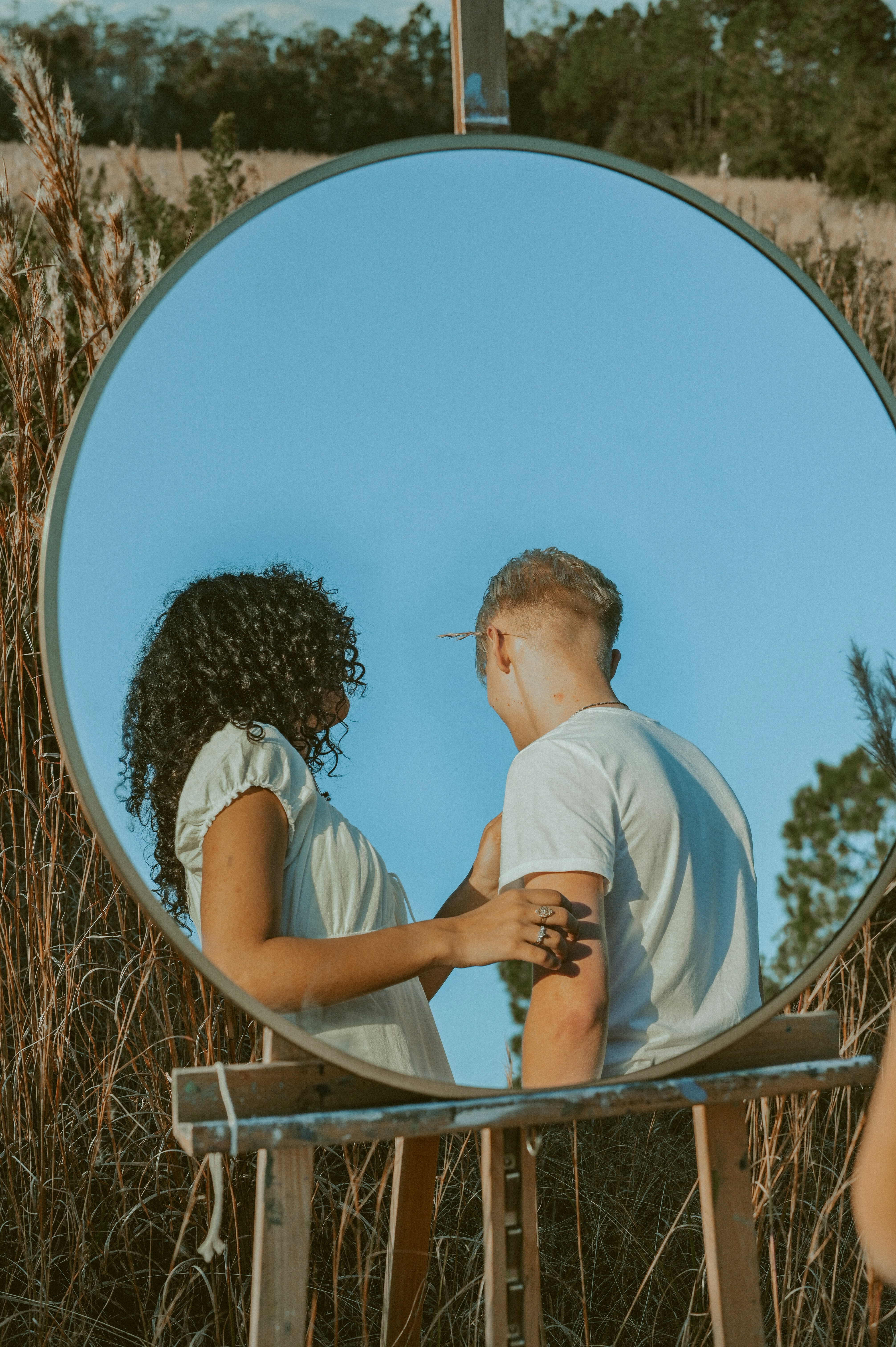 a man and woman kissing in front of a mirror