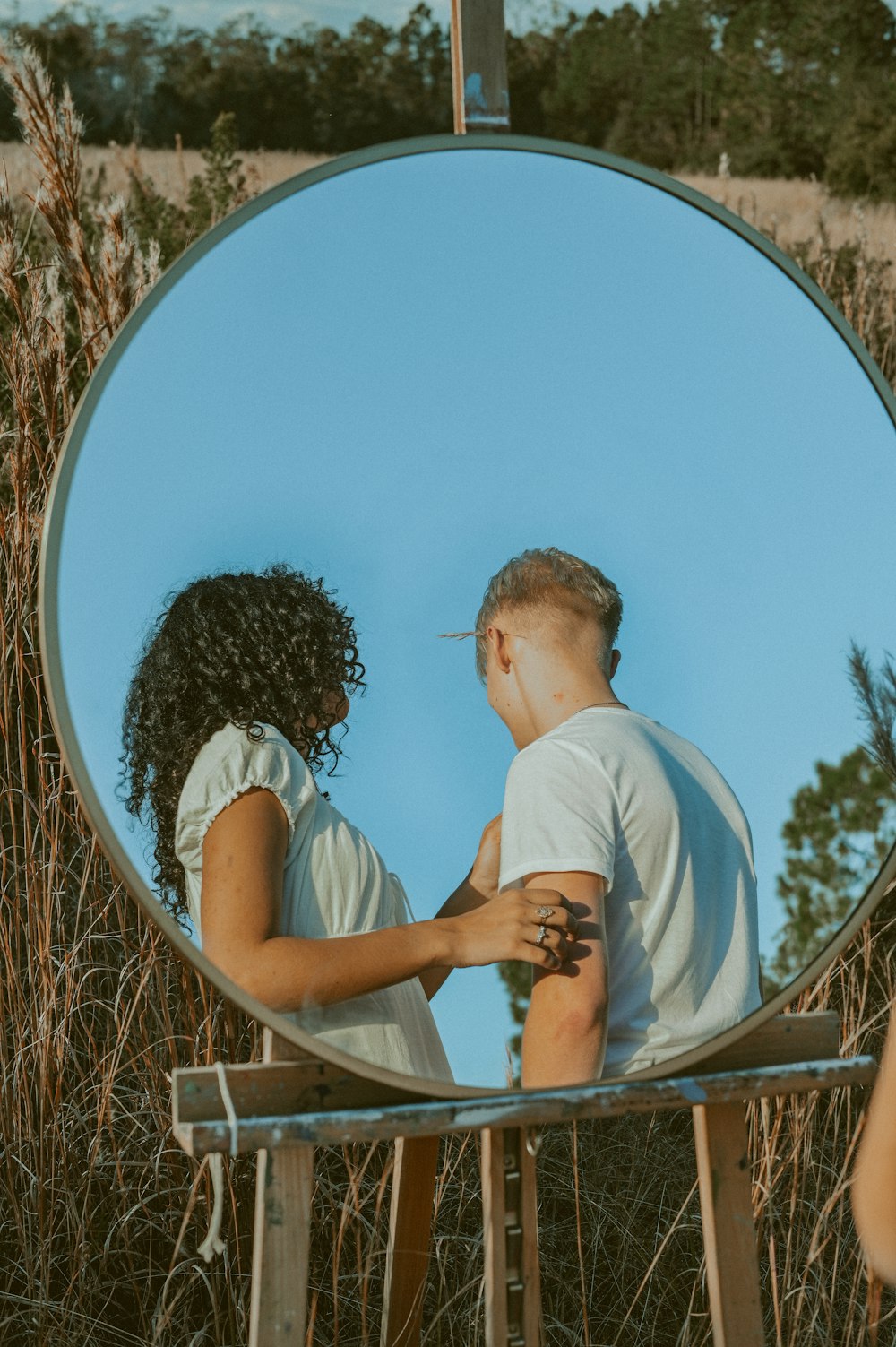 a man and woman kissing in front of a mirror