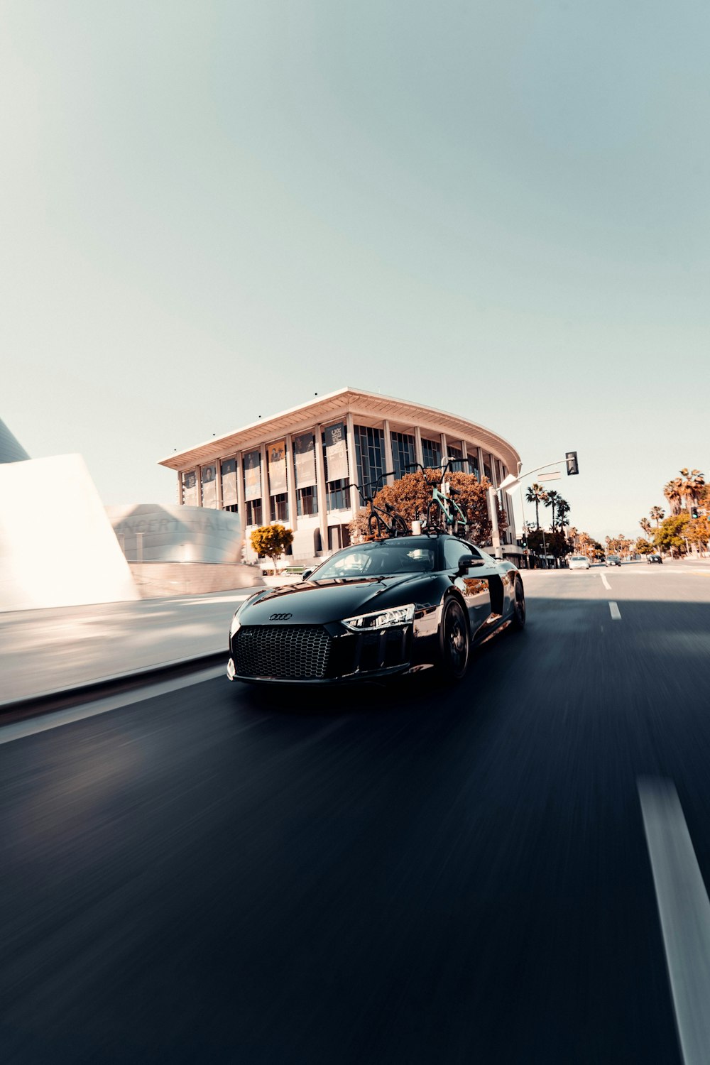 a black sports car driving on a road in front of a building