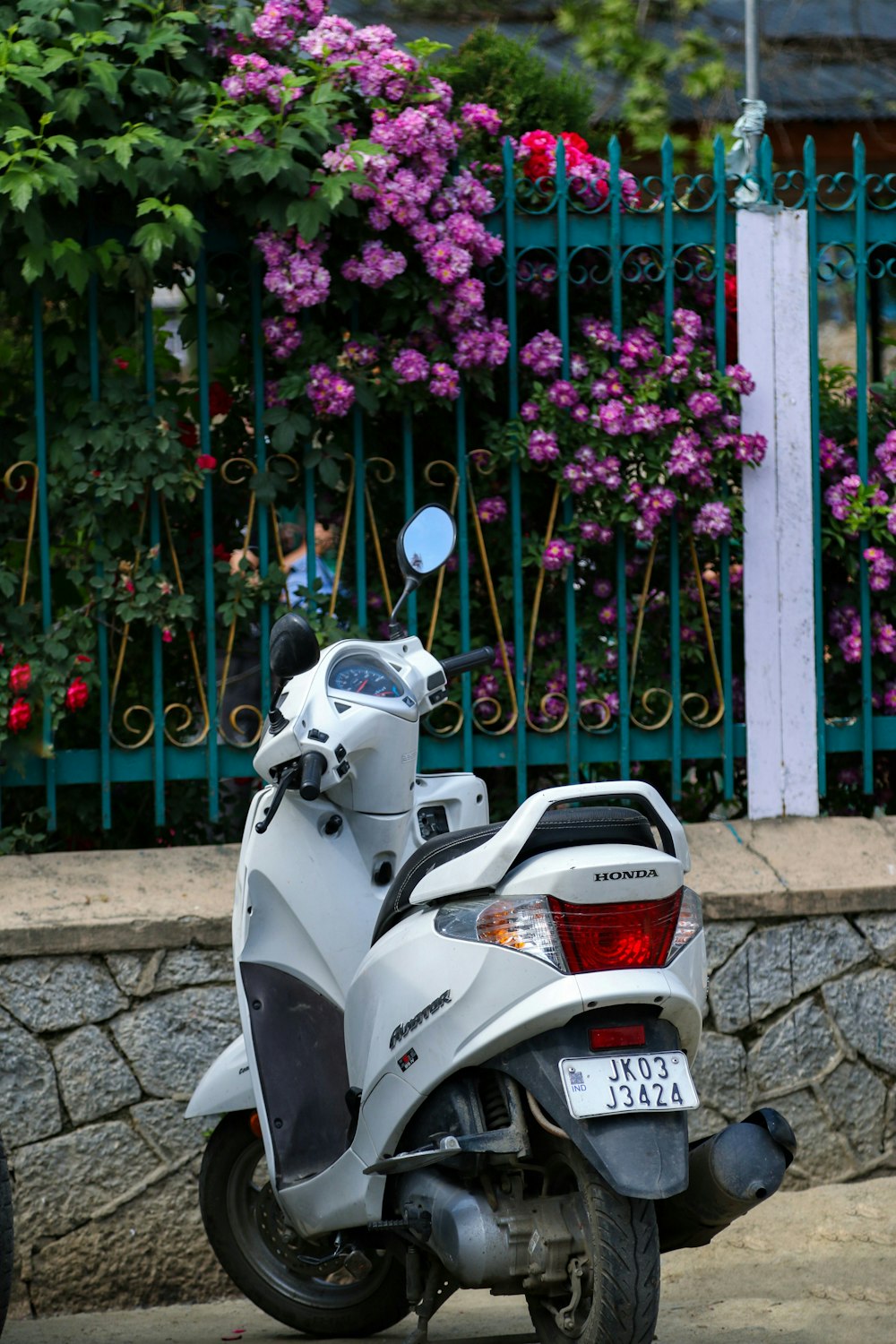 uma motocicleta estacionada em frente a um portão com flores sobre ela