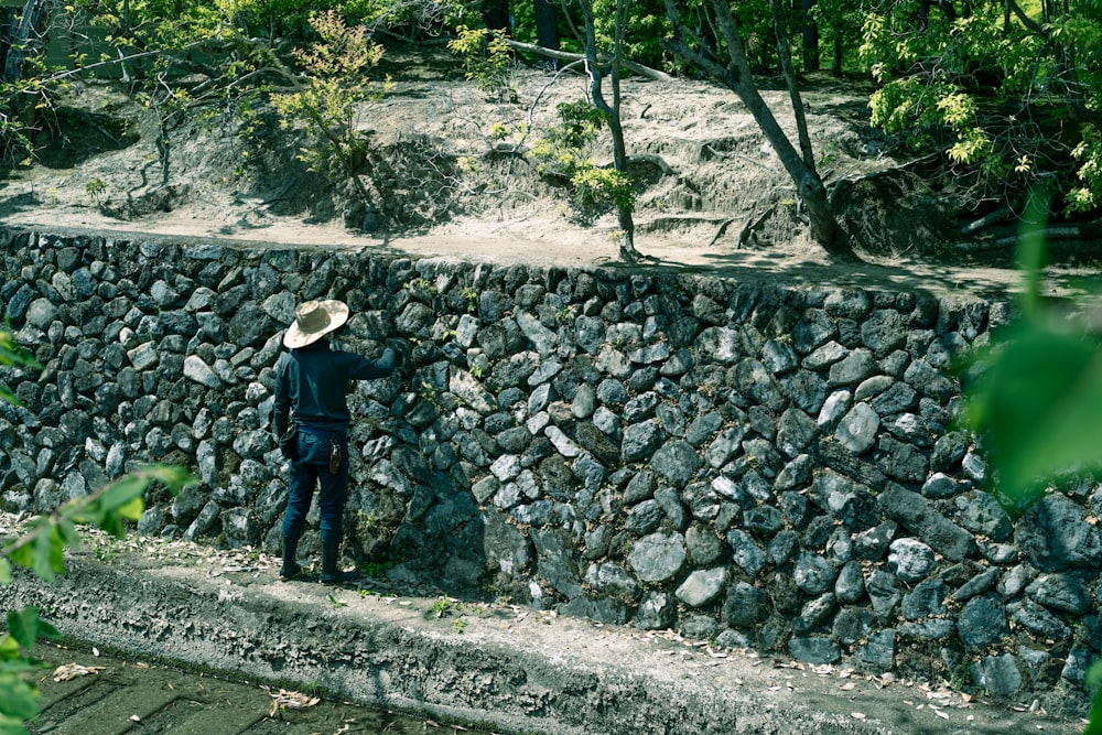 a person standing next to a rock wall