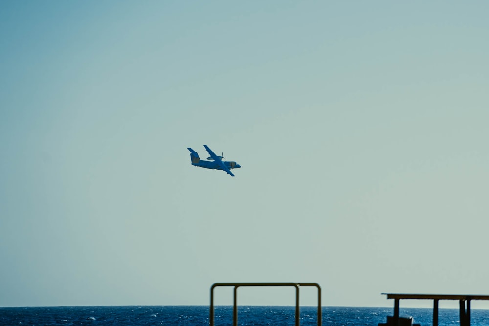 um avião azul voando sobre um cais