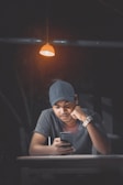 a man wearing a hat and looking at a cell phone