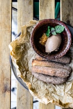A plate of churros dusted with cinnamon sugar next to a cup of rich chocolate sauce.