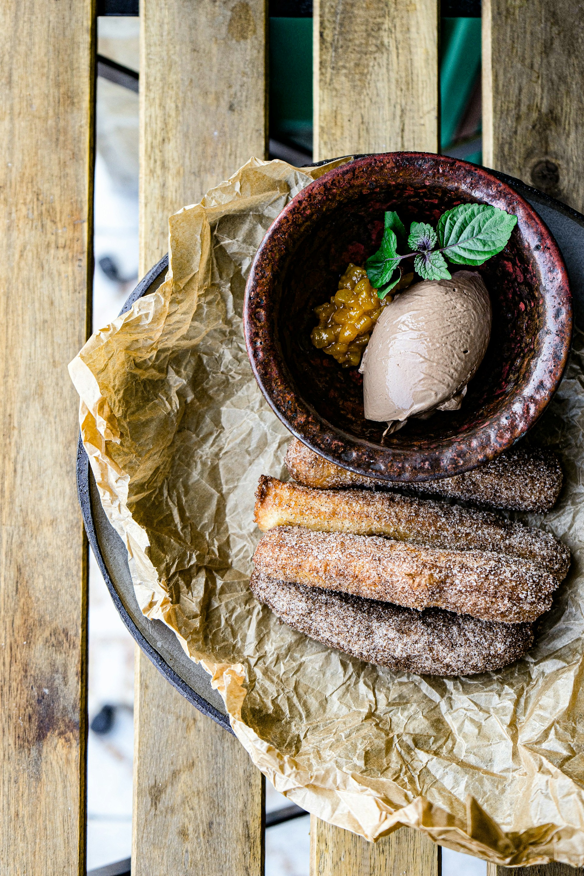 Close-up of golden churros dusted with cinnamon sugar, served alongside a rich chocolate dipping sauce on a pink plate.