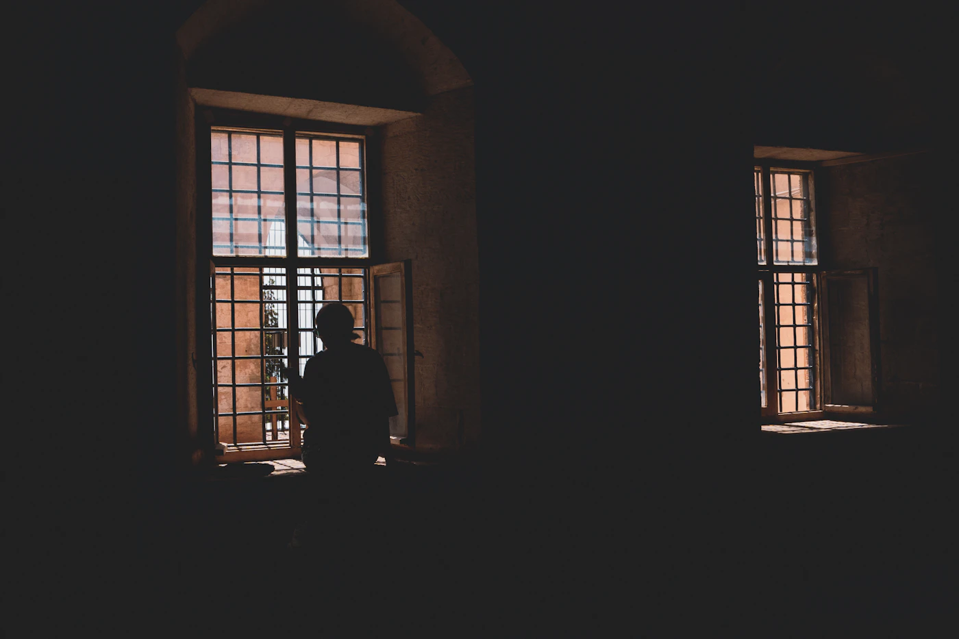 Silhouette of a person at a window in a dark room