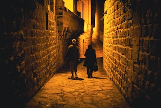 a person walking down a street next to a brick wall
